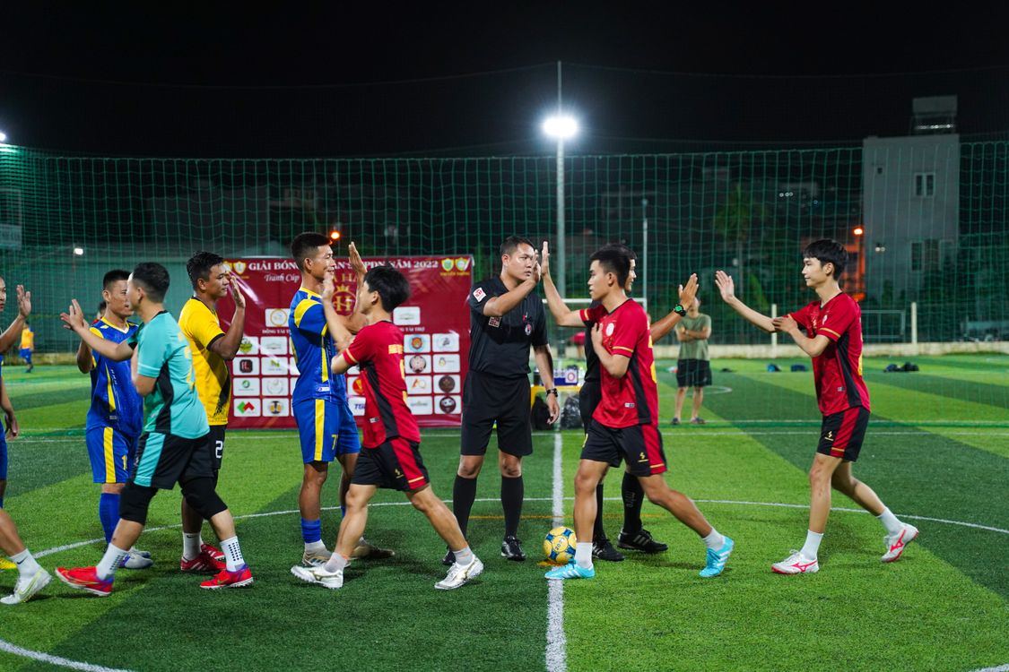 Community sports players on artificial turf pitch under stadium lights